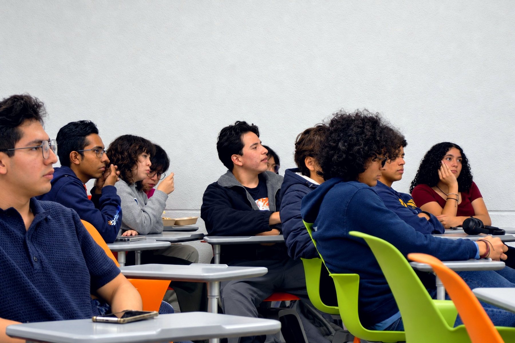 Estudiantes escuchan con atención en un salón durante una sesión de debate